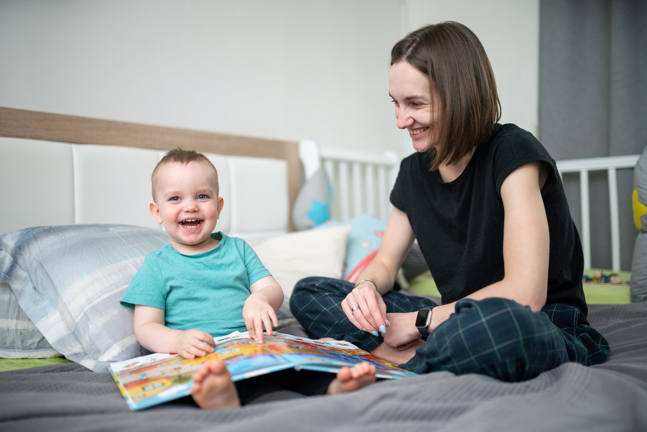 Happy baby boy and woman on the bed reading a book