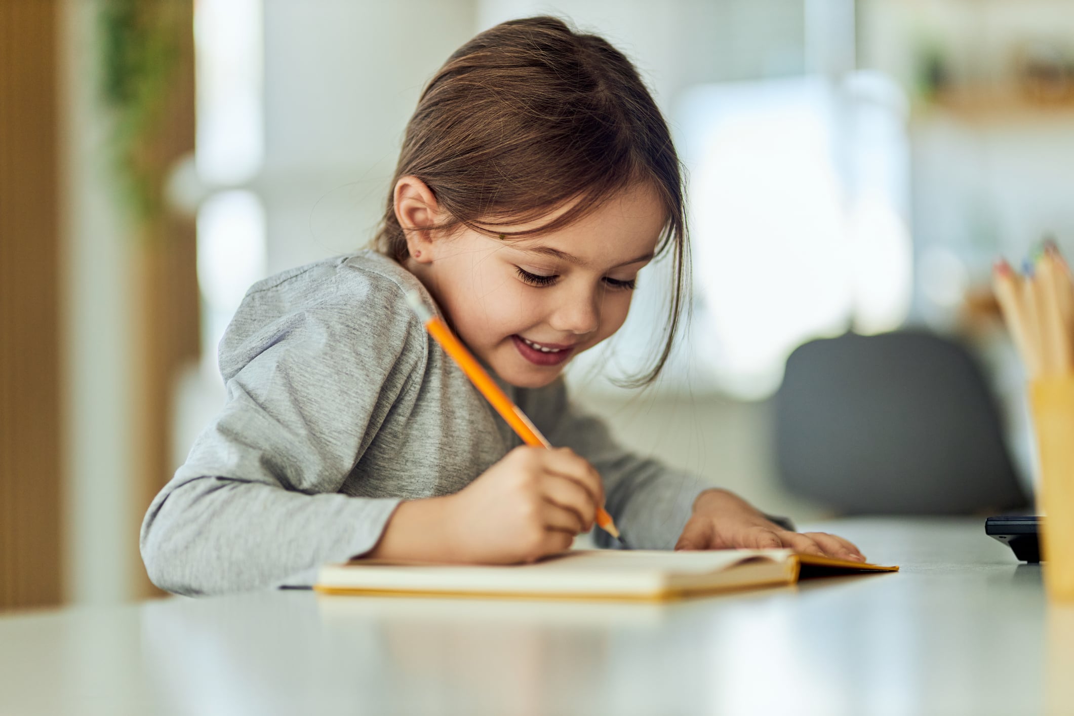 Happy female child, enjoying the weekend, writing something in her notebook.